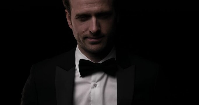 handsome elegant businessman posing with attitude and smiling on dark background 