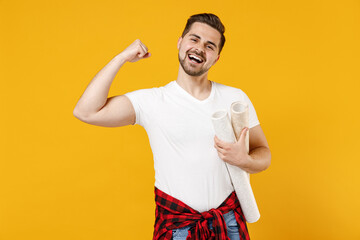 Young employee fun handyman man wear t-shirt holding wallpaper rolls do winner gesture isolated on yellow background studio. Instruments accessories for renovation apartment room. Repair home concept.