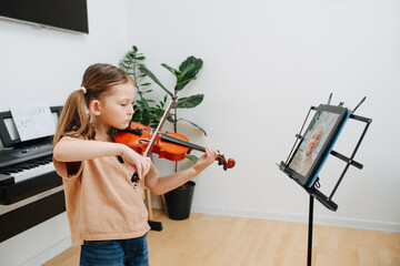 Keen little girl plays violin, showing her progress to her grandma in video chat