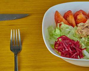 Delicious Tuna and Green vegan salad decorated with silver curtlery on a wooden background