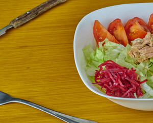 Delicious Tuna and Green vegan salad decorated with silver curtlery on a wooden background