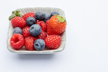 Strawberry raspberry and blueberry on a plate on white background