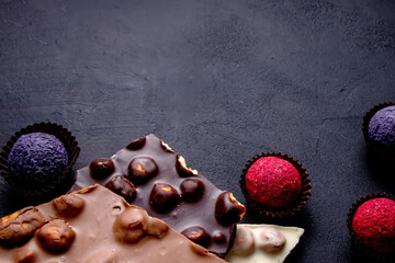 Chocolate bar, crushed pieces of dark chocolate and nuts. Praline Chocolate sweets. Copy space