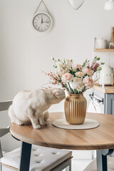 Spring bouquet on wooden table in the kitchen. Scandinavian style. White wooden background. Bright kitchen interior.