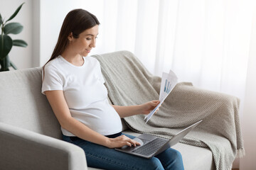 Fototapeta premium Distance Job Opportunities. Pregnant Woman Working With Documents And Laptop At Home