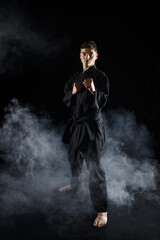 Obraz premium Male karate fighter in black kimono, combat stance