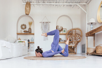 Young woman working out at home doing advanced yoga exercise
