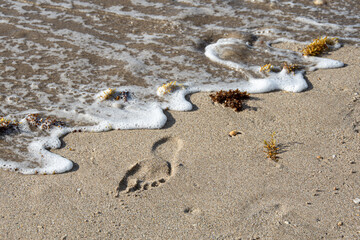 Surf washing away footprints in sand