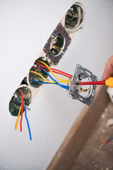 Hands of electrician installing socket in gypsum wall
