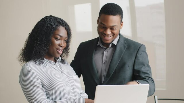 Male professional mentor teaching intern training new worker consult customer look at laptop screen at office helping female client. Two colleagues business people working together discuss project