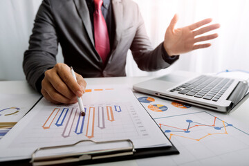Cropped shot group of businesspeople using graph chart and computer laptop, tablet discussing about business plan together in modern office.