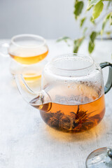 Chinese flower tea brewed in a transparent teapot with two cups .