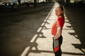 Fitness model girl posing wearing sport clothes with hands on hips and earphones.