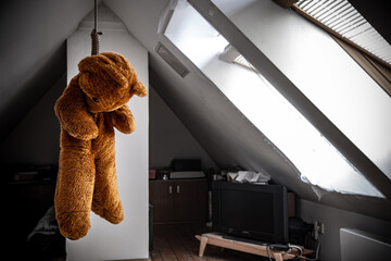A teddy bear hanging in a noose in the attic room