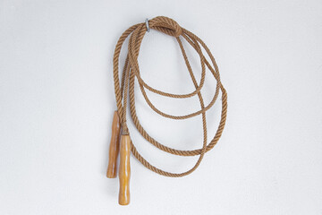 A old skipping rope hanging on a white wall.