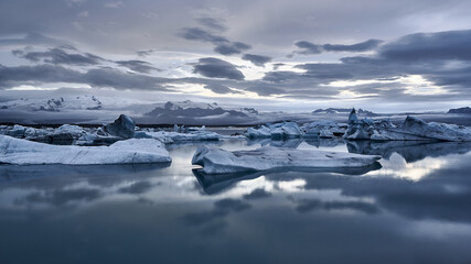 Closeup shot of an arctic sea with small icebergs and the clouds reflected in the water