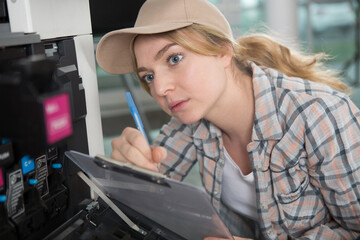 woman with clipboard inspecting photocopier