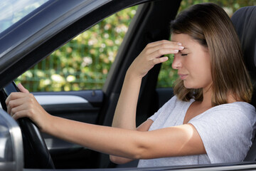 Obraz na płótnie Canvas young female driver with headache in a car