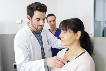 male doctor checking senior patient using stethoscope