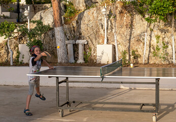 happy boy playing ping pong on a sunny summer day, horizontal.