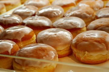 many round donuts in icing sugar on the counter in the supermarket side view