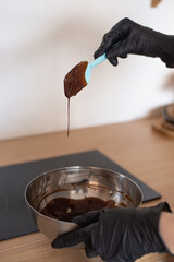 the pastry chef has melted the chocolate; the chocolate drips from the spoon into the bowl