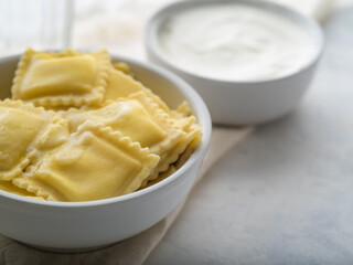 Dumplings with cottage cheese and sour cream. Delicious dumplings drizzled with butter in a dazzling white plate. Nearby is sour cream. A very tasty and nutritious dish of Slavic cuisine. Breakfast.