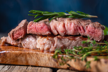 Grilled fish fillet with herbs and spices. Dish for picnic and weekend. Blue background. Close-up cutting board. Greens. Pastel shades.