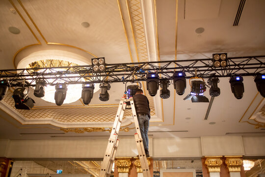 Male Light Technician Is Arranging Fixing Stage Lights On Truss For Show Rehearsal. Stage Light System Set Up