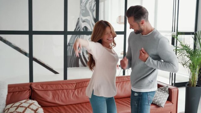 Playful Young Heterosexual Couple Having Fun And Dancing At Home Together