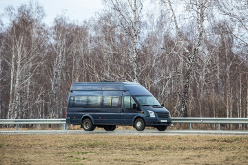 Obraz na płótnie Canvas minibus moves along country road along birch forest