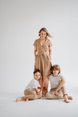 A mother and her two sons in beige and white clothes pose for a photo shoot 