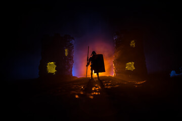 Fototapeta premium Medieval battle scene. Silhouettes of figures as separate objects, fight between warriors at night. Creative artwork decoration. Foggy background.