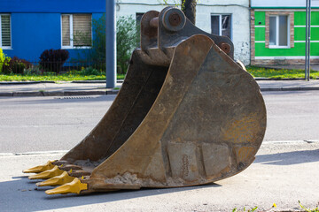 Dirty excavator bucket on the sidewalk. © Alex