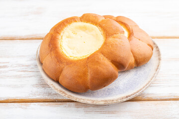 Sour cream bun on a white wooden background. Side view.