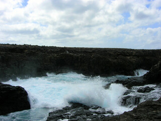 Splashes and waterfalls left by the breaking wave on the rocks of the cave of the blue eye of Barracona, natural pool, Sal Island, Cape Verde