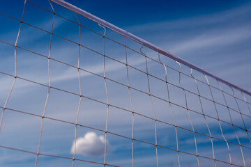 Volleyball net and a small cloud in the blue sky.