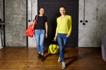 Women with travel bags returned to loft apartment from vacation.