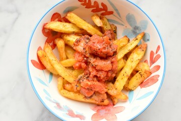 Bowl of fries with tomato sauce on top