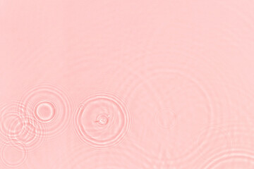 de-focused. Closeup of pink transparent clear calm water surface texture with ripples, splashes and bubbles. Trendy abstract summer nature background. Coral colored waves in sunlight.