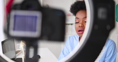 young female doctor recording a lecture on camera, creating video content, consulting a patient remotely