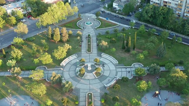 Park - round paved playground in a garden surrounded by trees and grass, as the central square of green city recreational area in urban environment. Aerial drone view of walkways and podium.
