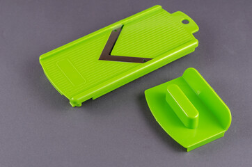Sharpening and cutting pusher for vegetable slicer on gray background.