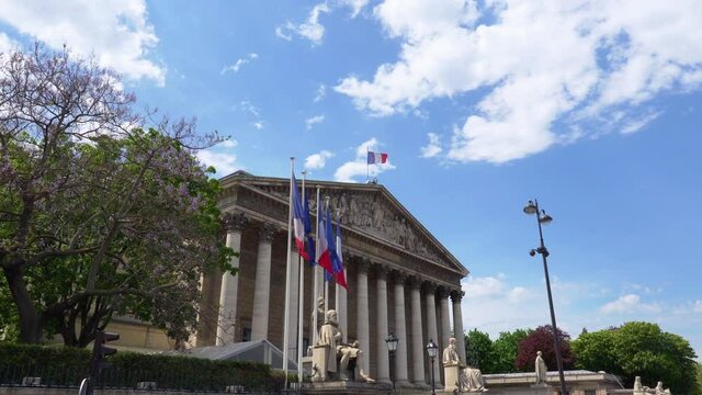French National Assembly building with French and EU flags waving - Paris, France.