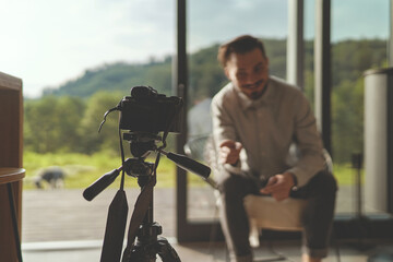 Front view of successful businessman recording interview with camera and tripod
