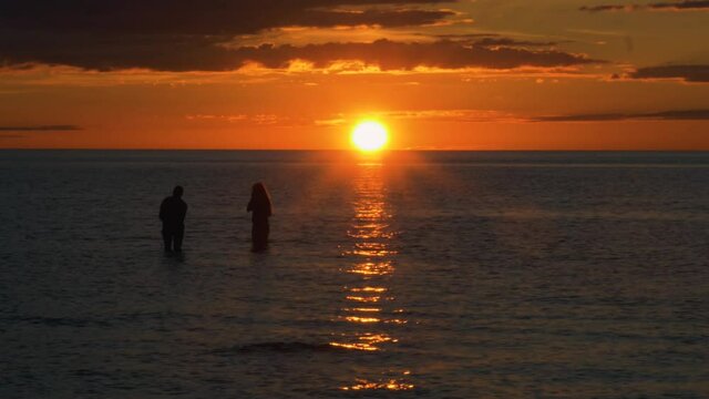 Silhouette girls playing in shallow ocean enjoying midnight sun, in Scandinavia