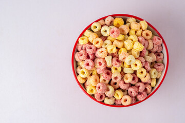 Cereal flakes in red bowl with copy space,Breakfast concept.Food with delicious fruity taste and fruity colours.It's made with maize,wheat,and barley.topview and copy space.white background.