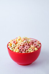 Cereal flakes in red bowl with copy space,Breakfast concept.Food with delicious fruity taste and fruity colours.It's made with maize,wheat,and barley.topview and copy space.white background.