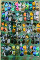Colorful sunglasses for summertime on a sell board on streets.