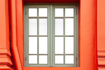 Antique light green wooden windows and classic red cement wall